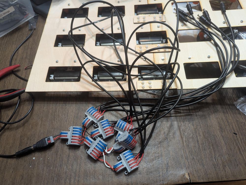 A cascading series of lever wire connectors, joined to each other with hookup wire, start with a single barrel jack to wire connector and end by sending voltage/ground to 15 different power wires to power 15 PCBs from a single cable.