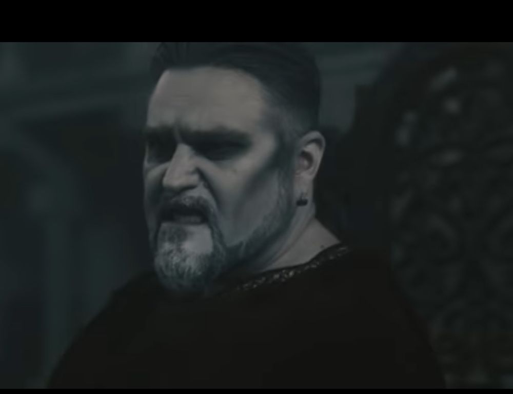 Screenshot from the Powerwolf video to “My Will Be Done.” Attila Dorn is a corrupt Emperor who is making a disgusted face right after a servile priest (keyboardist Falk Maria Schlegel) presents him with a Bible. The song is about a leader using religious imagery inappropriately to hold on to illegitimate power and the video implies that this Emperor is defeated by Matthew Greywolf’s sick guitar solos.