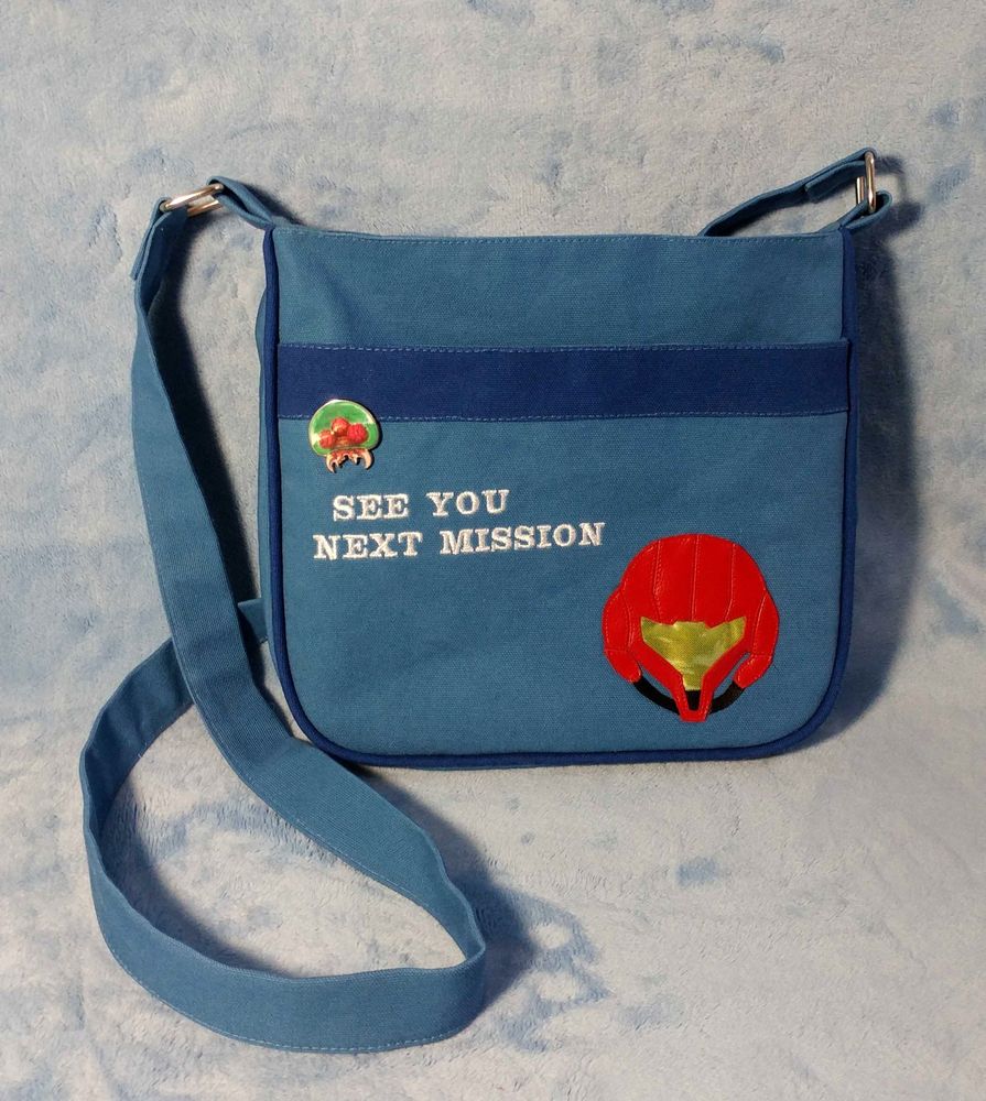 A blue shoulder bag with a Samus helmet applique and embroidered text that says "SEE YOU NEXT MISSION". This was my previous daily bag. I like my personal bags to have piping, as it helps add structure and a bit of class.