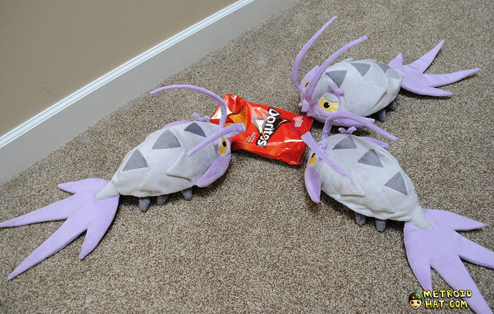 Three wimpod plushies surrounding a Doritos bag like the ravenous monsters they are.
