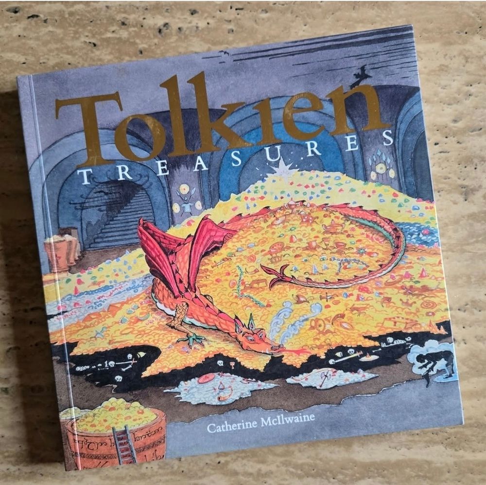 The book is titled Tolkien Treasures. There is a painting of the red dragon named Smaug sitting on top of his hoard of gold. Bilbo Baggins is in front of him, but he is invisible. Shown as a cloud around him. They are in a large underground tunnel.