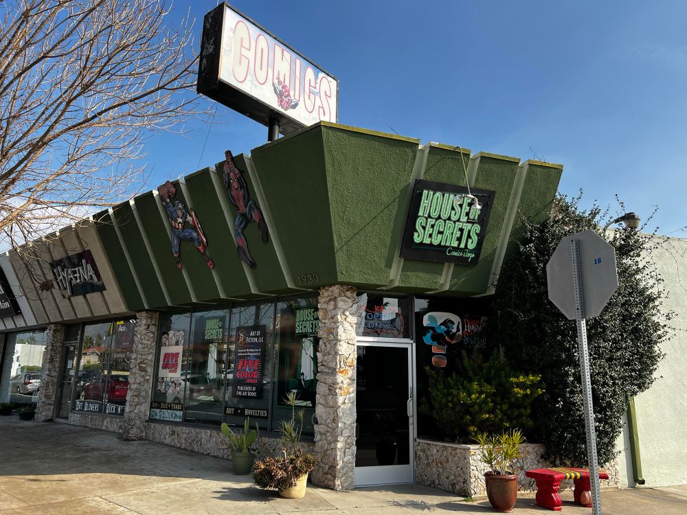 It’s a picture of the exterior of house of secrets comic bookstore in Burbank. It’s a stone façade on the bottom and on the top. There are several characters, including Captain America and Spider-Man and assigned reading House of secrets.
