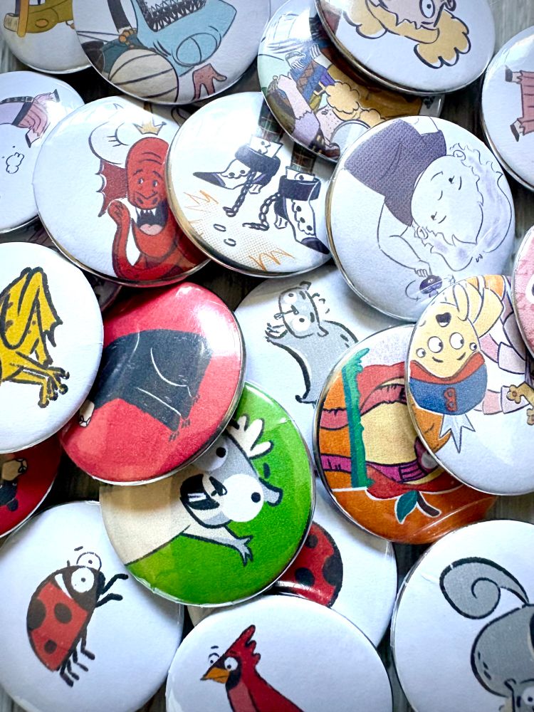 A bunch of pins that include characters from the graphic novel story spinners, and the picture book gray squirrel loses it, including a cardinal, a ladybug, some gray squirrels, a frog, a bear, a dragon water spiders,
 pirates, and sharks
