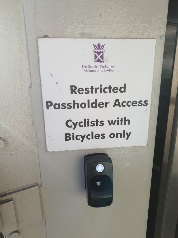 A sign that says the following:

The Scottish Parliament
Pàrlaimid na h-Alba

Restricted Passholder Access
Cyclists with bicycles only