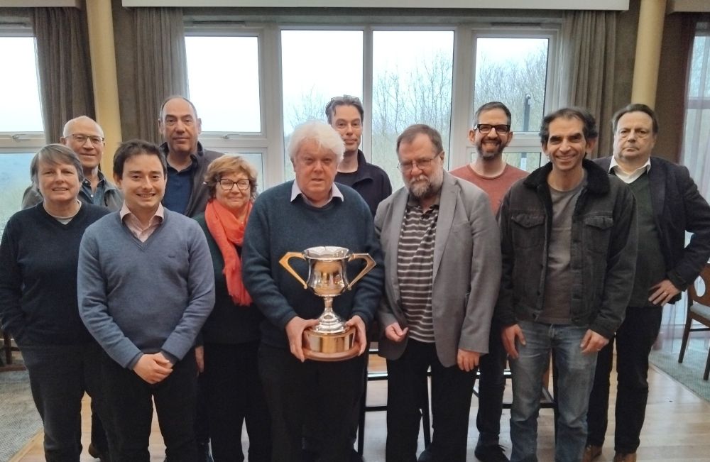 Photo of eleven people who made up the winning London team, the middle person is holding a trophy