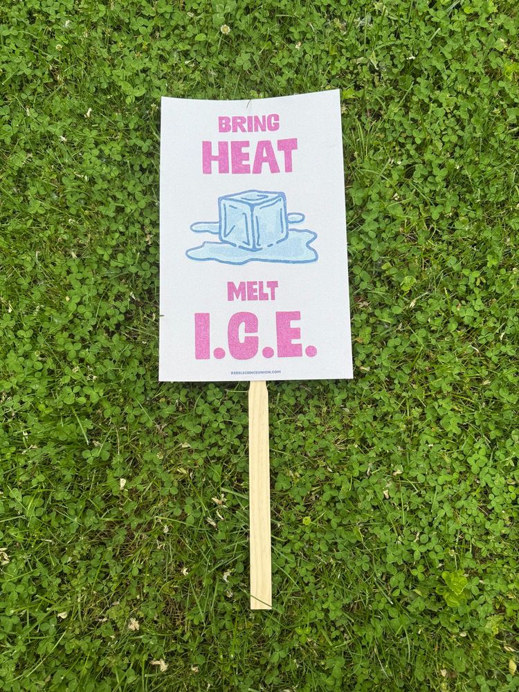 Protest posters on the ground. "bring heat melt I.C.E." with a melted ice cube