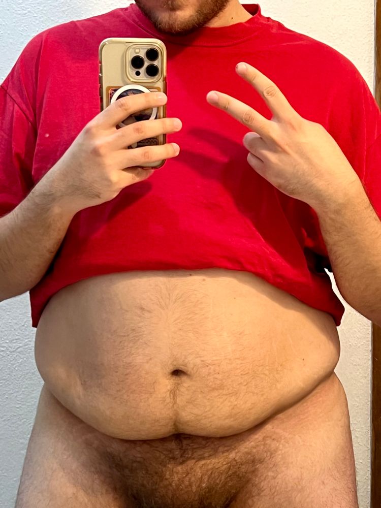 A photo of me in a red shirt showing my belly.