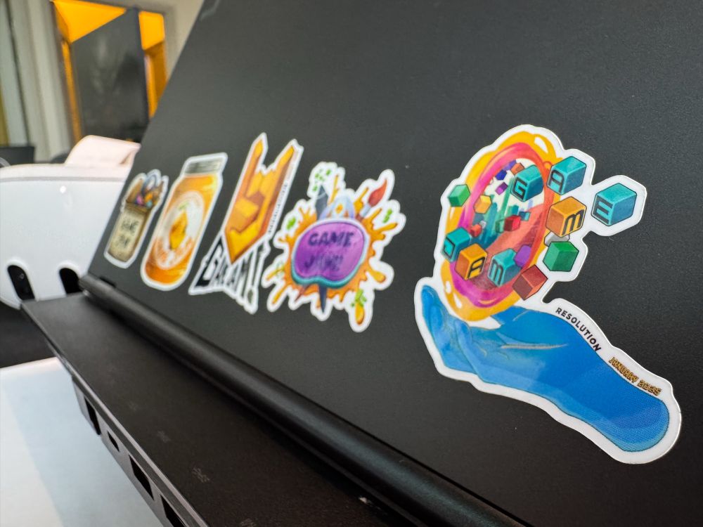 Game jam stickers from past and current Resolution Games Game Jams on a laptop 