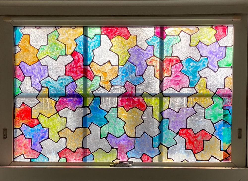 Window with DIY fake stained glass in the pattern of the "kite"-shaped aperiodic monotile filled in with a rainbow of different
colors