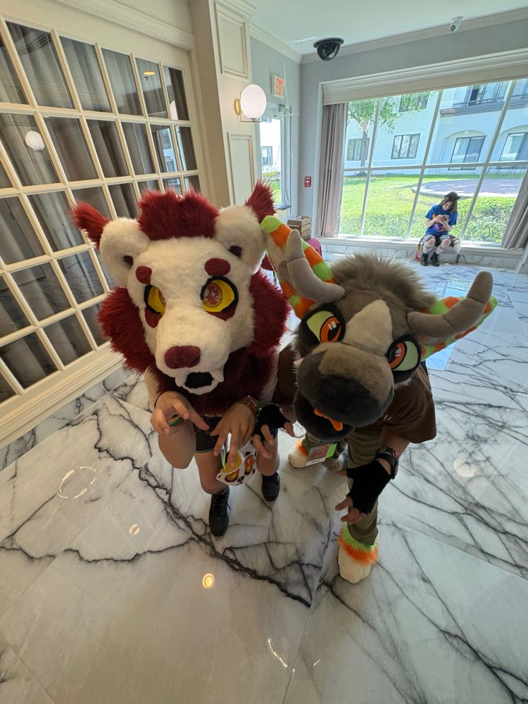 Two furries with their hands up like paws, while looking up at the camera 