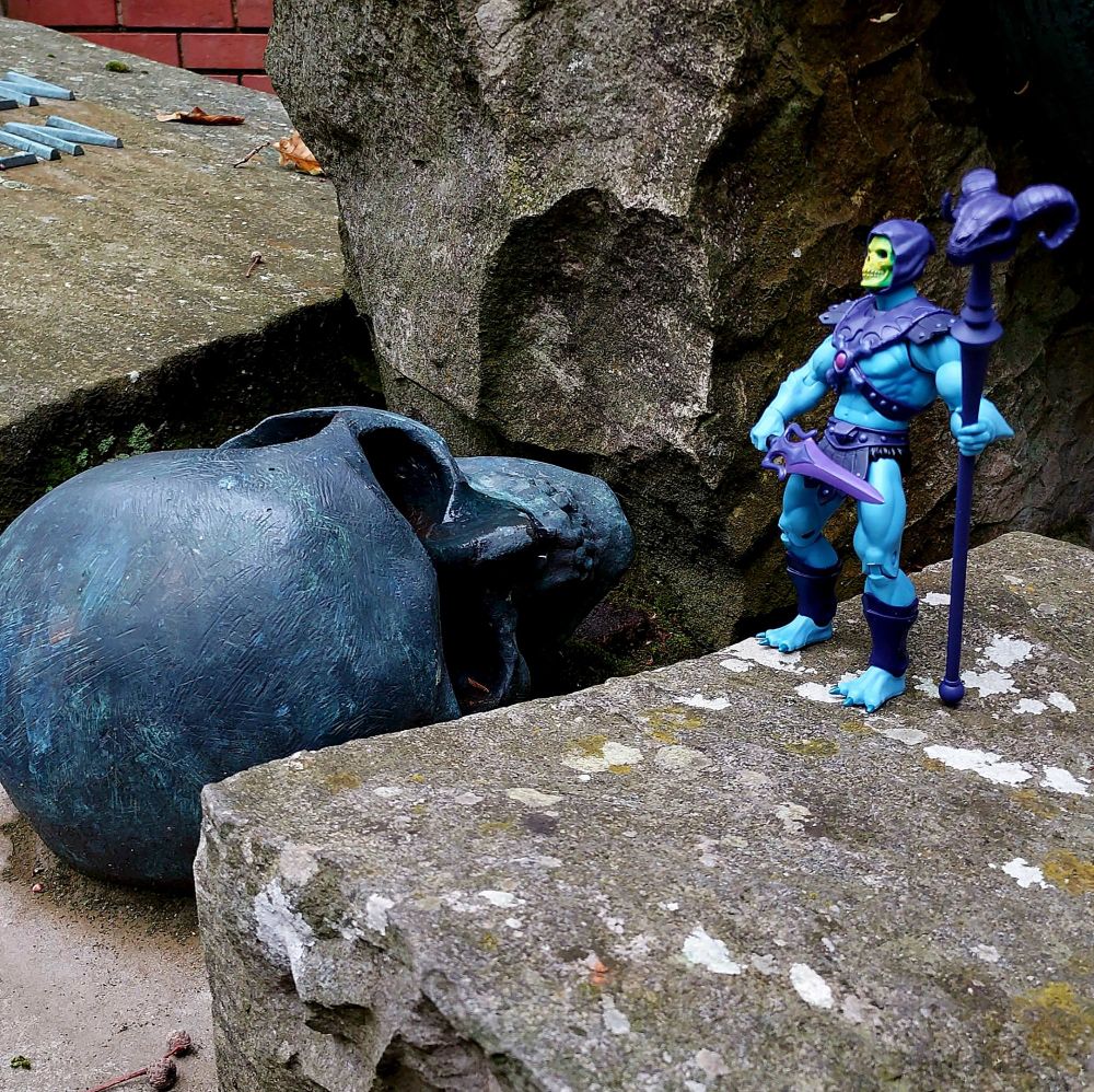 Skeletor looks down on a fallen bronze skull 