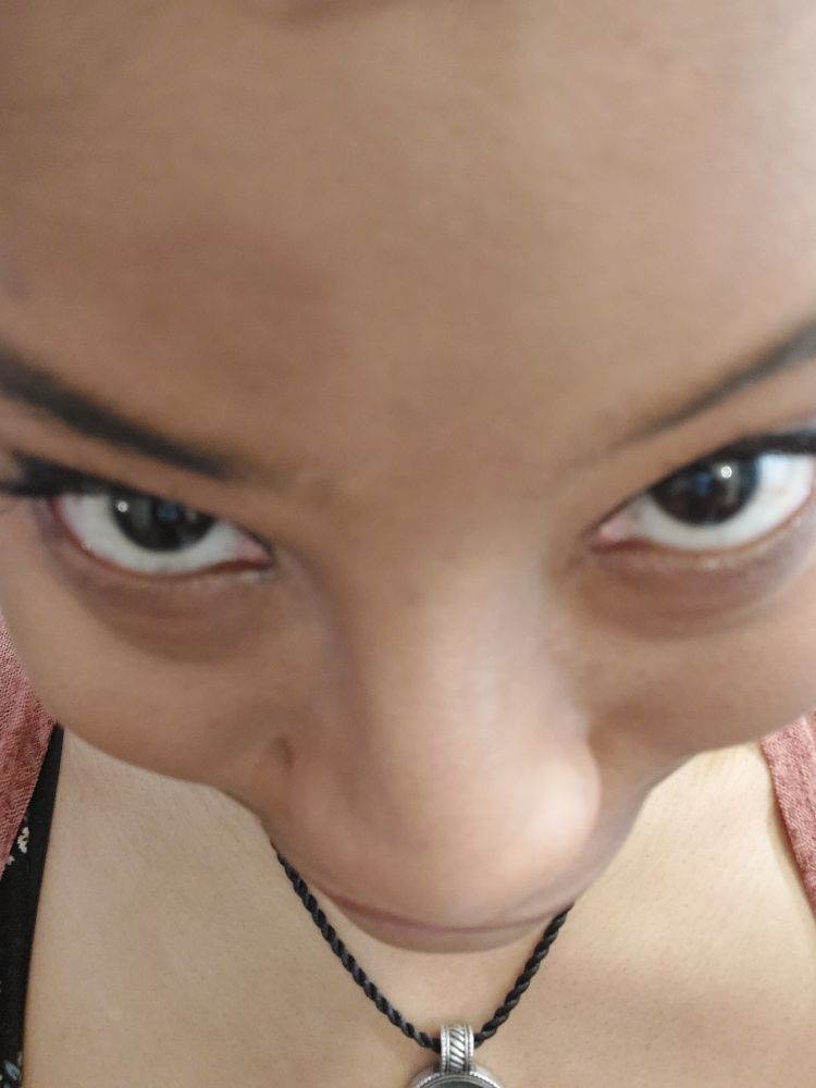 an overhead shot of a black woman but it's just her forehead mostly, looking up at the camera anime style