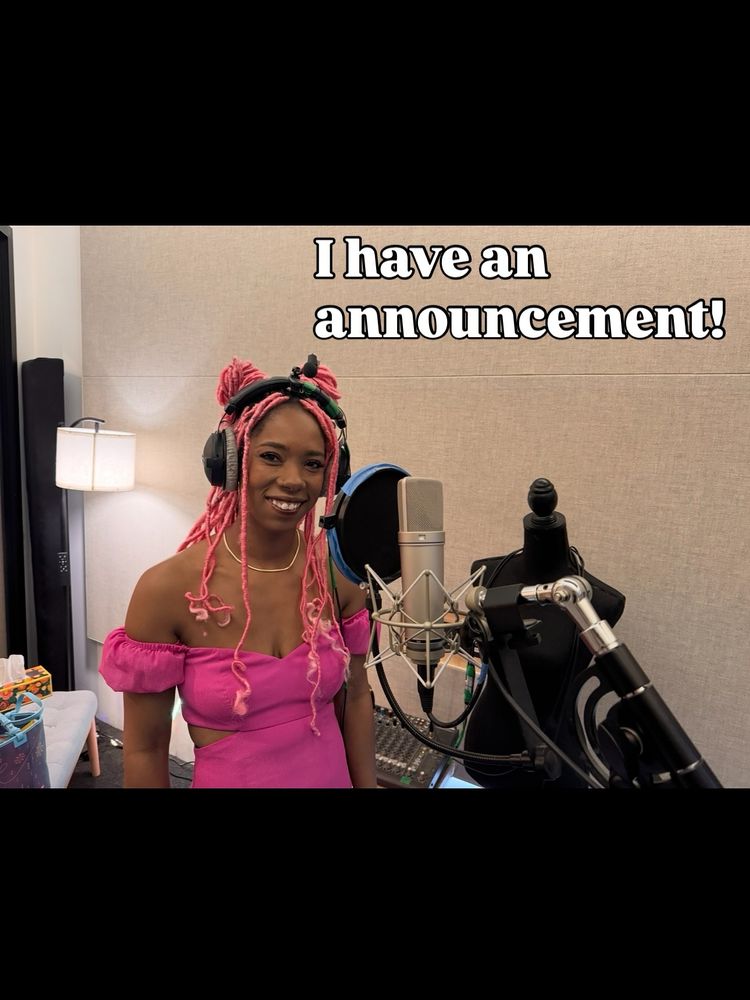 Krystina stands in front of a microphone in a recording booth in a pink off the shoulder dress with pink locs in her hair smiling, next to text that says "I have an announcement"