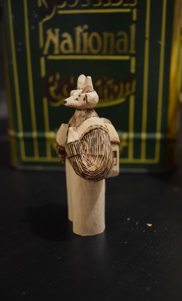 wooden deer sculpture, made of wood. he has a backpack