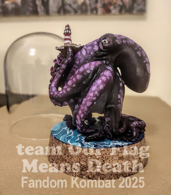 A tiny, black and purple figurine of Kraken Ed holding a lighthouse made by team OFMD for Fandom Kombat.