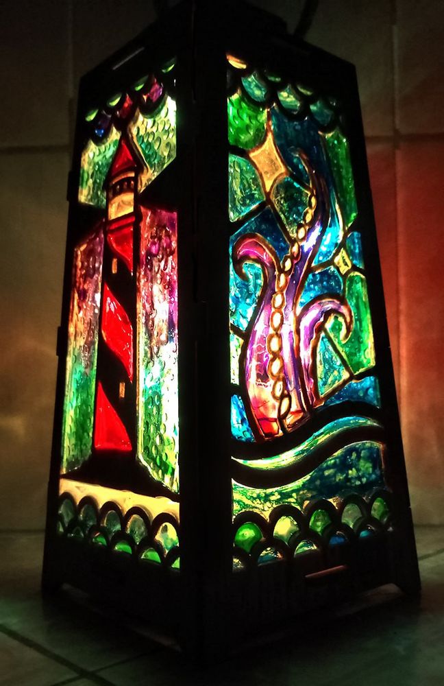 A handmade OFDM-themed lantern with a lighthouse on the left panel and kraken on the right.