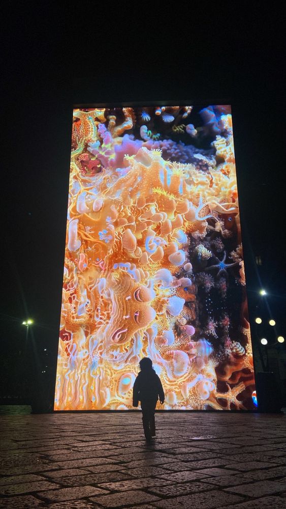 A child stands in front of a large LED screen displaying 'sediment nodes'