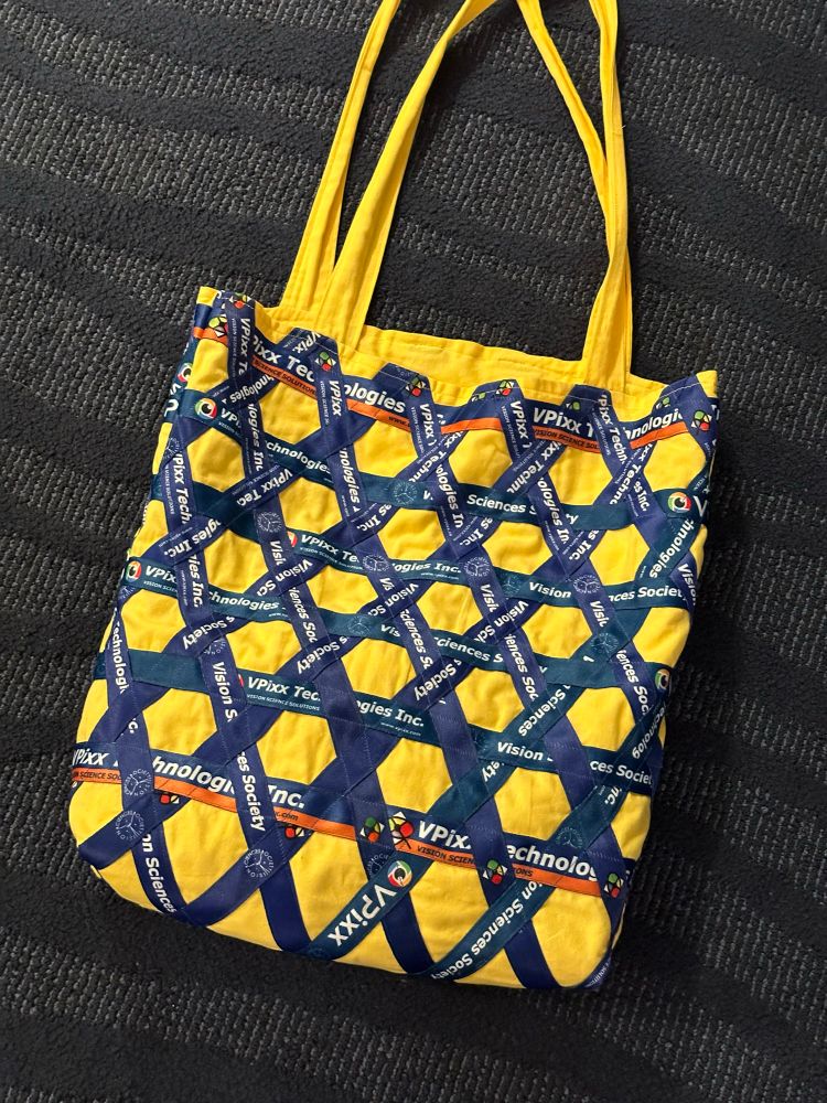 A yellow tote bag decorated with a lattice of vpixx-branded VSS lanyards 