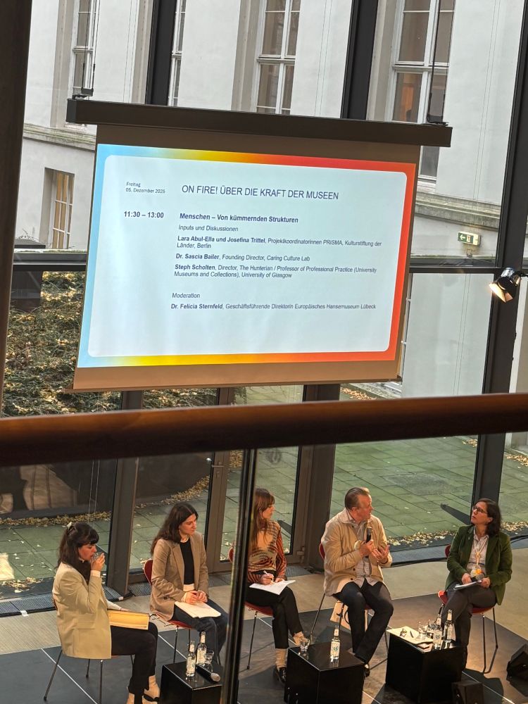 Die beitragende vier Personen  und die Moderatorin sitzen auf dem Podium 