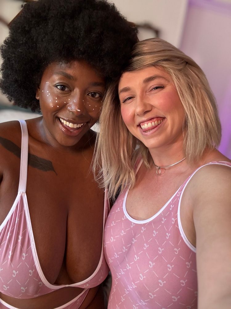 Dutch Coco and Lilith Eden are in matching pink lingerie sets smiling at you