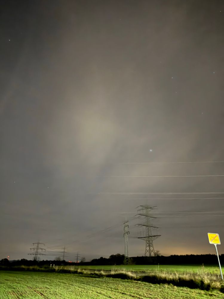 Nacht über dem Feld, strommasten und Ortsschild 