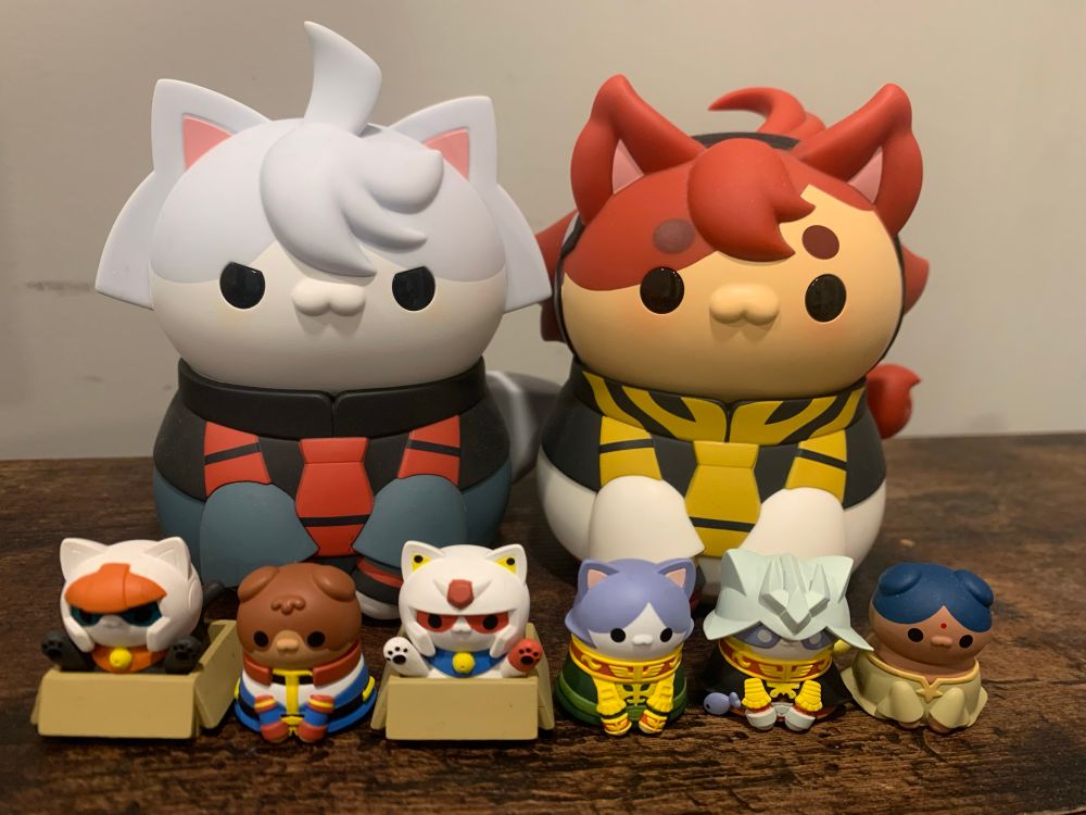 A collection of Gundam figurines where the characters are reimagined as cats. The characters: Miorine, Suletta, Guncannon, Amuro, Gundam, Garma, Char, Lalah