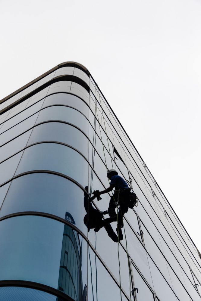2023-04-15 Tokyo Japan - Color photo looking up at a window cleaner working on the side a fully glass clad building. The overcast day creating a liminal space of soft light, all surfaces appearing equally clean.

Canon R6 50mm f4 1/4000s iso160