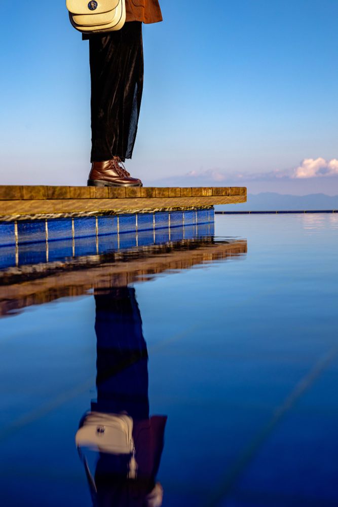 2024-10-13 Lake Biwa Japan - Color photo of a lady standing next to a shallow reflection pool lined with brilliant blue tiles, mountain ranges line the backgound.

Canon R6 70mm f7.1 1/640sec iso200