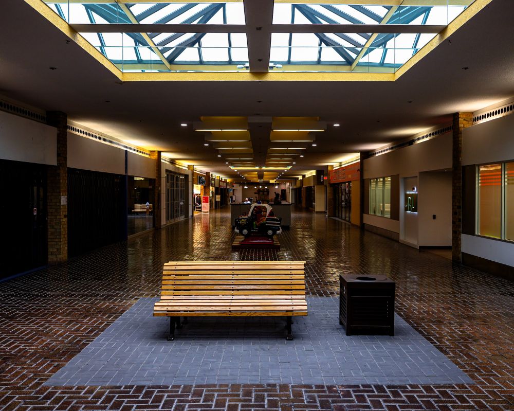 2025-07-08: Simcoe, Ontario - old wooden bench sitting in a Grey square lit by a skylight in a empty mall. Strong liminal space feel.
Canon R6 28mm 1/80sec f4.0 iso400