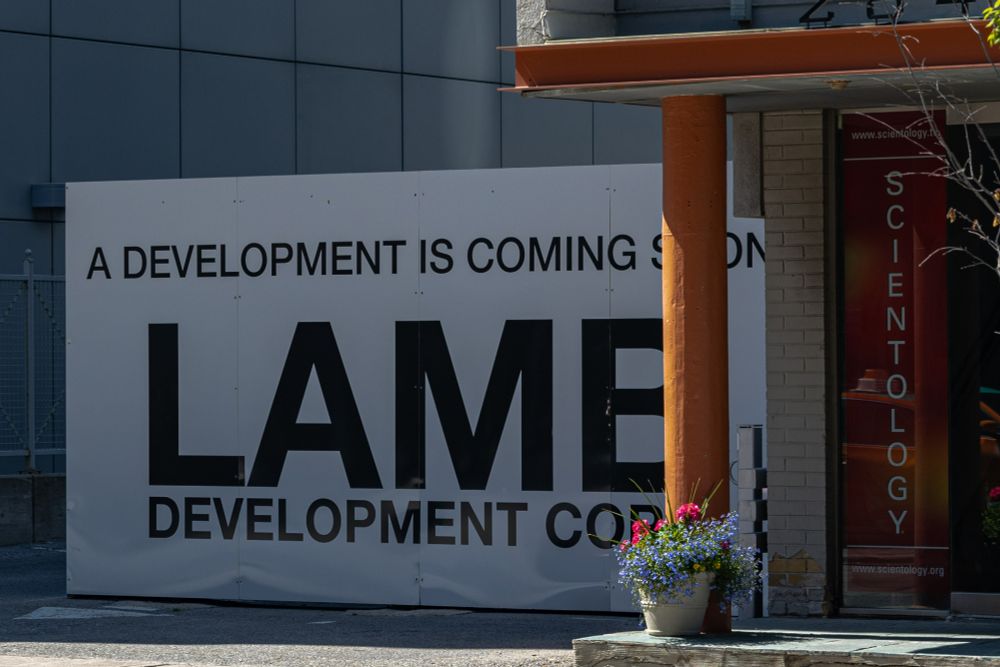 2020-05-26 Toronto, Ontario, Picture taken outside of 'Scientology' center, angled to show a constructions sign stating:
"A development is coming ----
LAME
Development co--"
