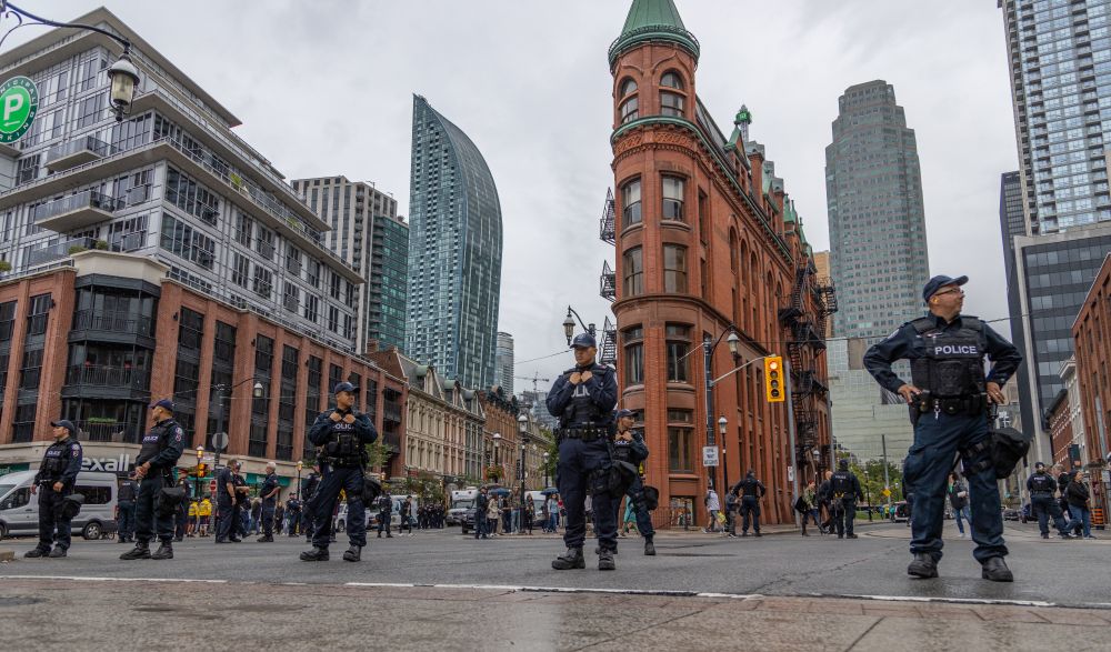 2019-09-28 Toronto Ontario: Colour photo of 'Front, Church, and Wellington' intersection red brick flat iron building. Crowd control police line the intersection in an even spaced pattern.

Canon R 24mm f4 1/640sec iso200
