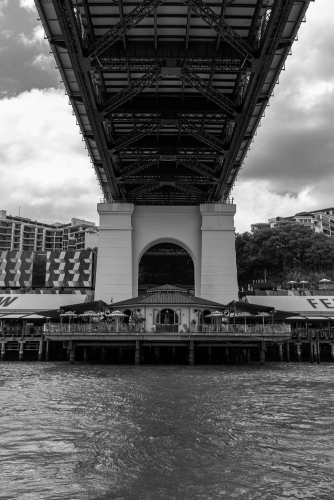 2025-01-27 Brisbane, Australia - Black and White photo from below the Story Bridge featuring the Felon's pub outdoor seating symmetrically aligned with the iron grid support.
Canon R6 35m f4 1/1250s iso400