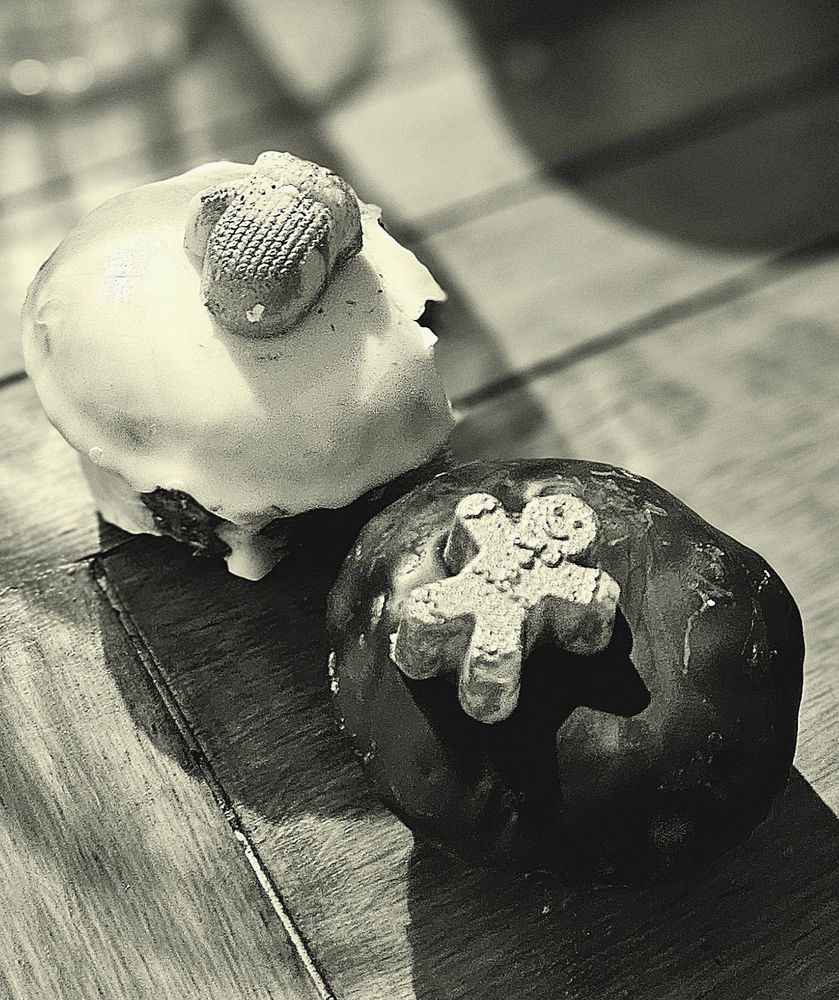 2 petits gâteaux au chocolat, format muffin, posé sur une table en bois. Un gâteau qui est recouvert de chocolat blanc durci, un autre recouvert de chocolat noir durci. 