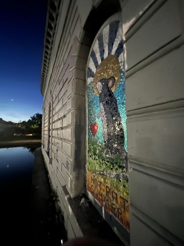 Mosaic of a patron saint rat with a sun behind it and a little heart. Below it states “Hot Rat Summer” 