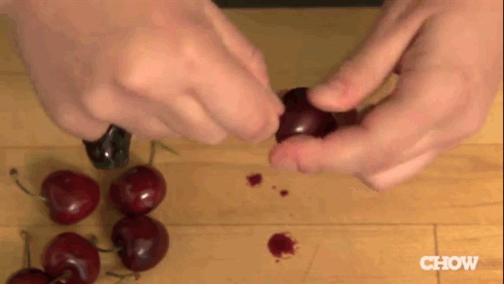 a person is peeling a cherry on a wooden table with a chow logo in the corner