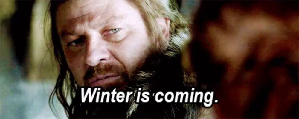 a man with a beard is looking at another man and saying `` winter is coming . ''