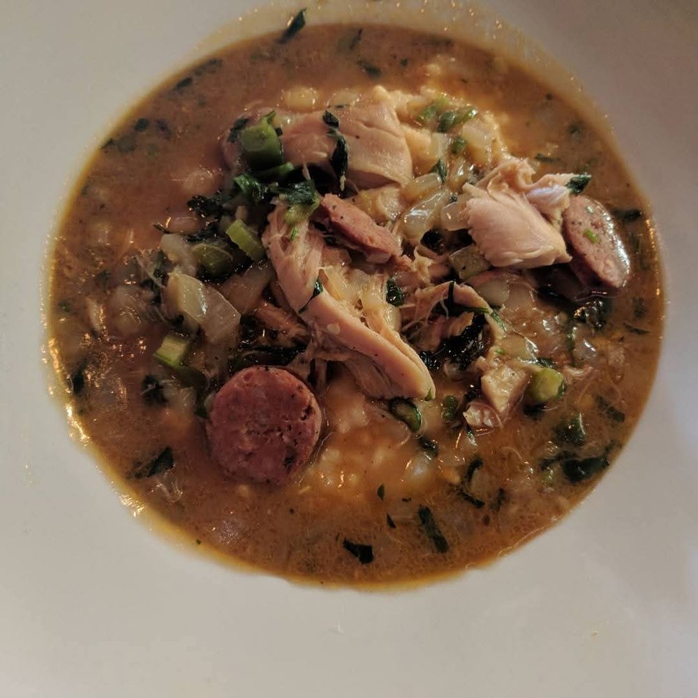 Shredded chicken and sausage medallions with onions, celery, peppers and herbs in a brown stew. Underneath, some grits poke out.
