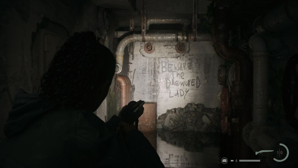 My character in Alan Wake 2 is walking through a partially flooded underground concrete cold war bomb shelter. Most of it is completely dark, except for the flash light you carry around the winding hallways. Spray painted  in the minimal cone of light available is the words, "Beware The Drowned Lady"