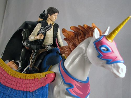 Han Solo and Batman toys cuddling gayly on the back of the flying unicorn from 
