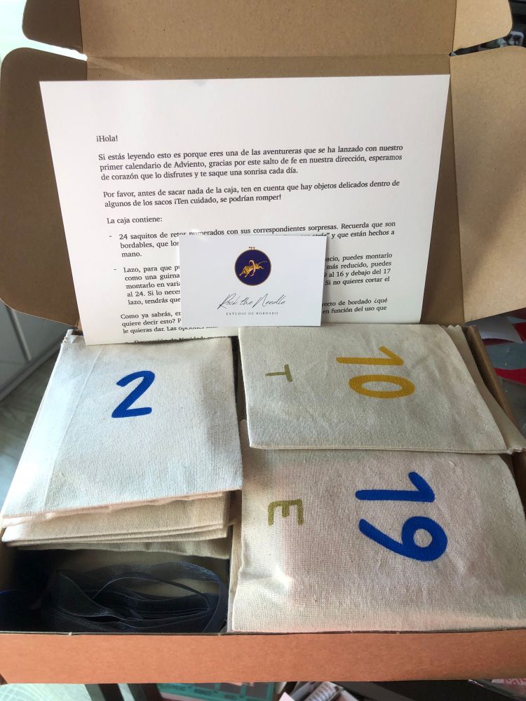 La caja abierta llena de los sobres de tela numerados que firman el calendario de adviento 