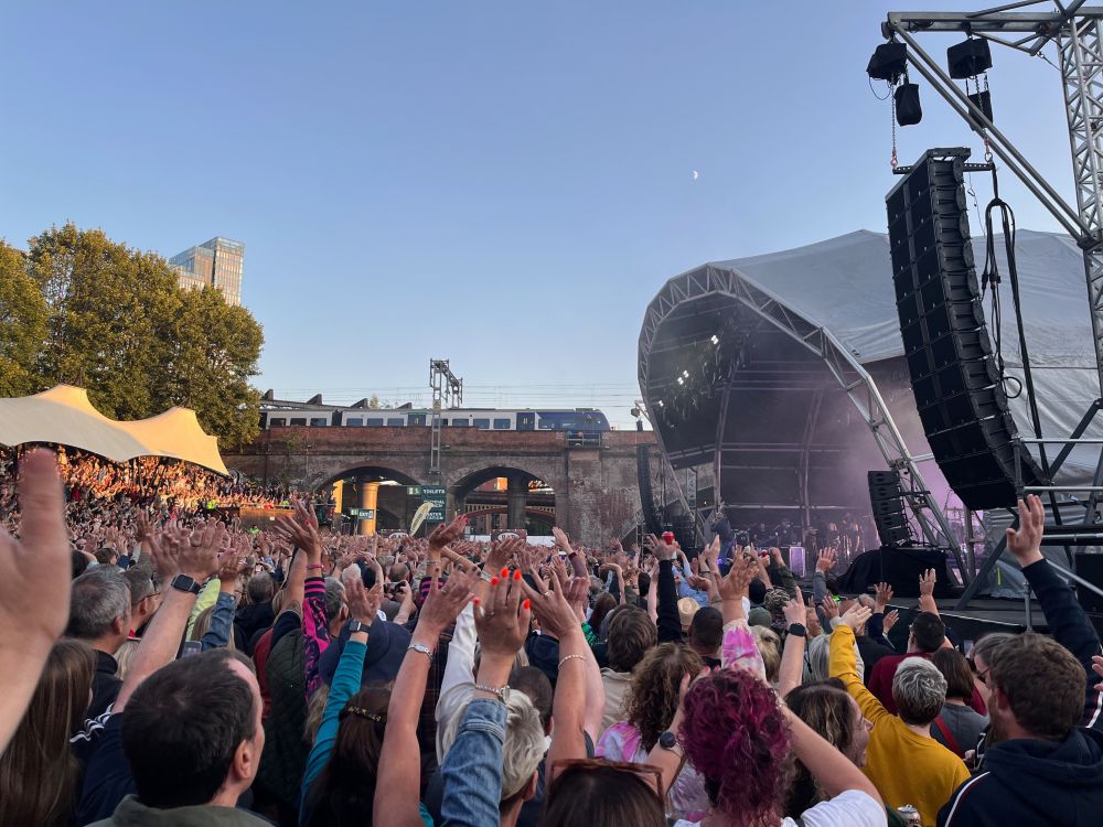 The crowd at Castlefield Bowl waving to a train. Guy Garvey on stage to the right can't quite believe what he's started.