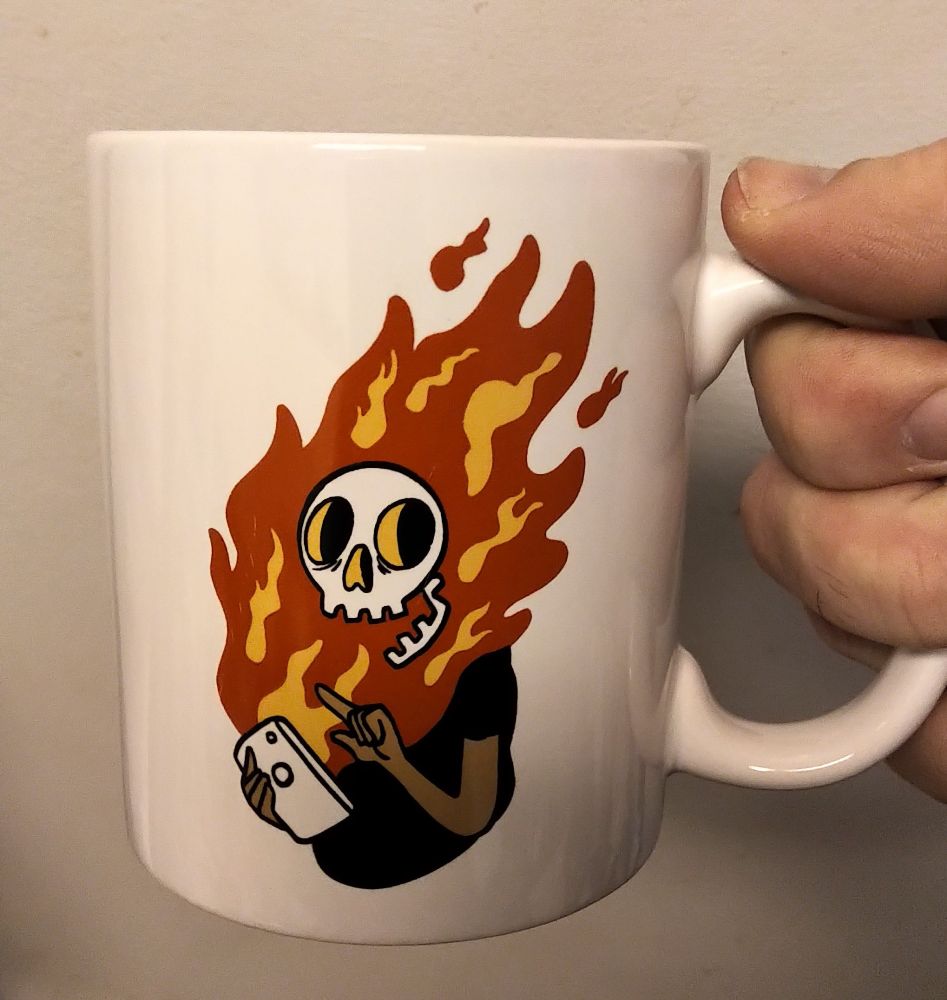 a mug with a cartoon image of someone checking their phone and having their whole face scorched off