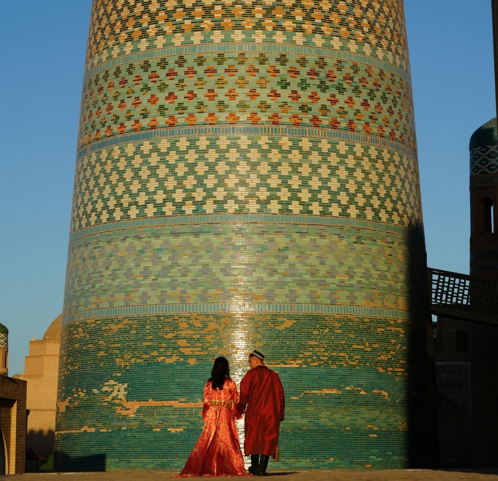 Couple wearing traditional Uzbek dress at base of Kalta Minor Minaret.