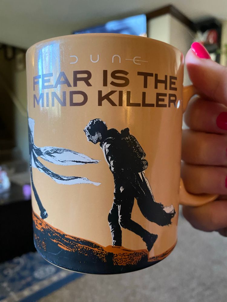 Coffee mug, brown with characters from DUNE on it and the words "fear is the mind killer"