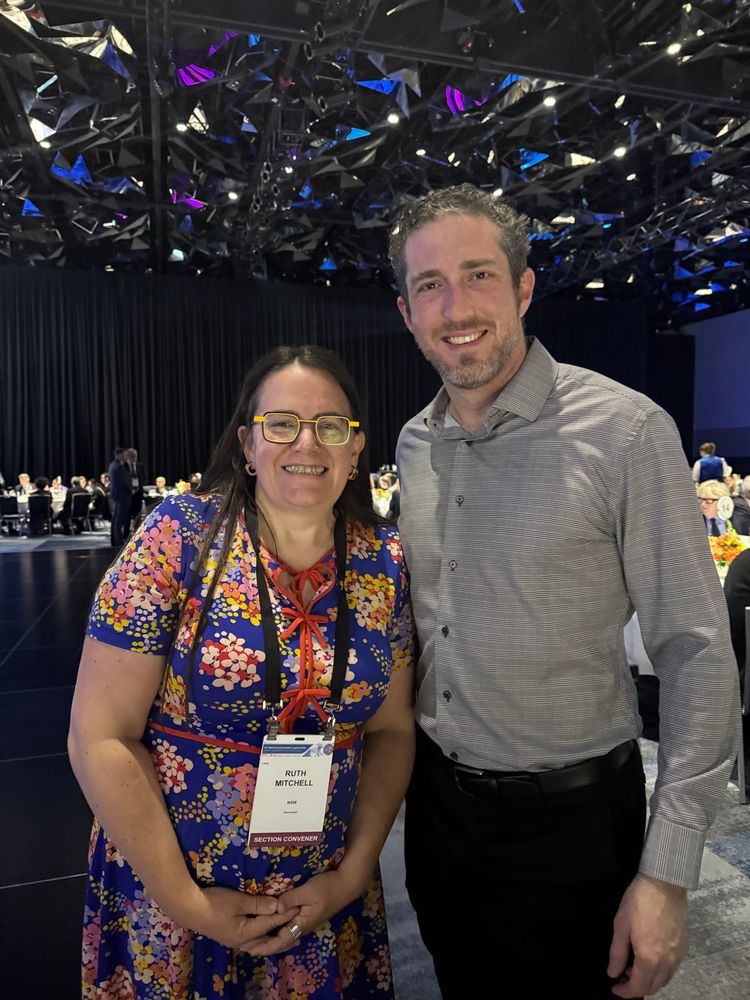 Ruth and Dr Glaucomflecken are standing and smiling. Ruth has yellow glasses. 