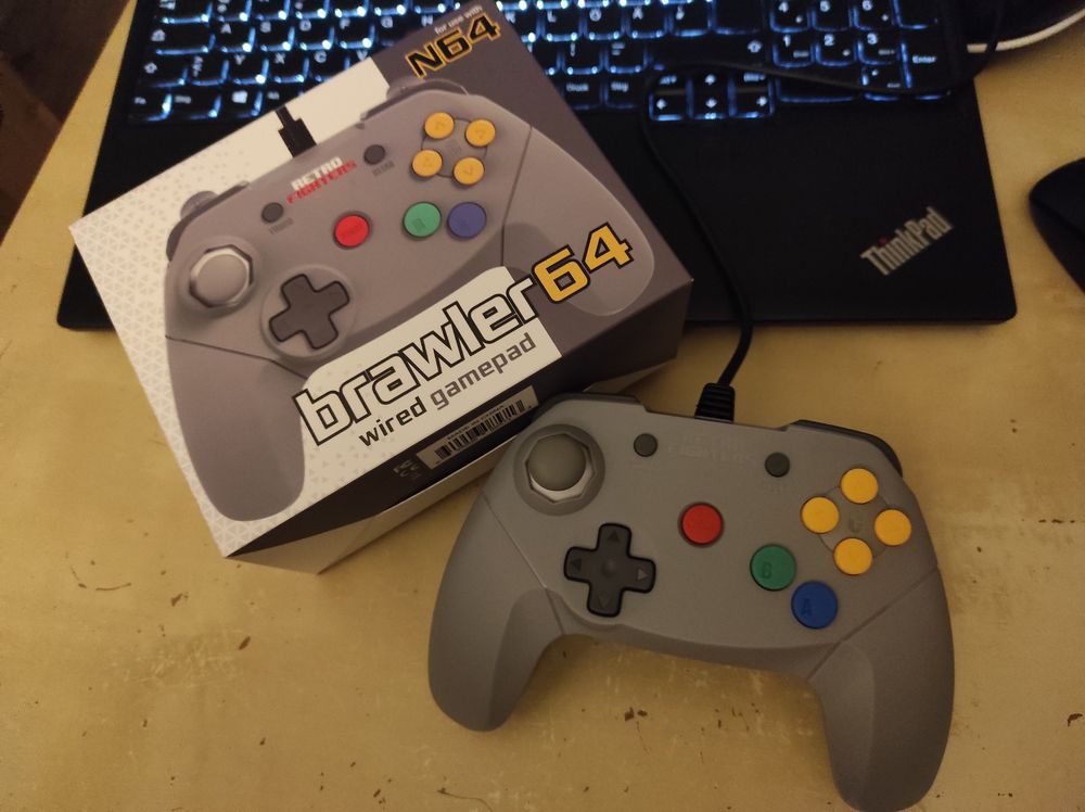 Photo of Brawler64 N64 controller in grey, next to its box 