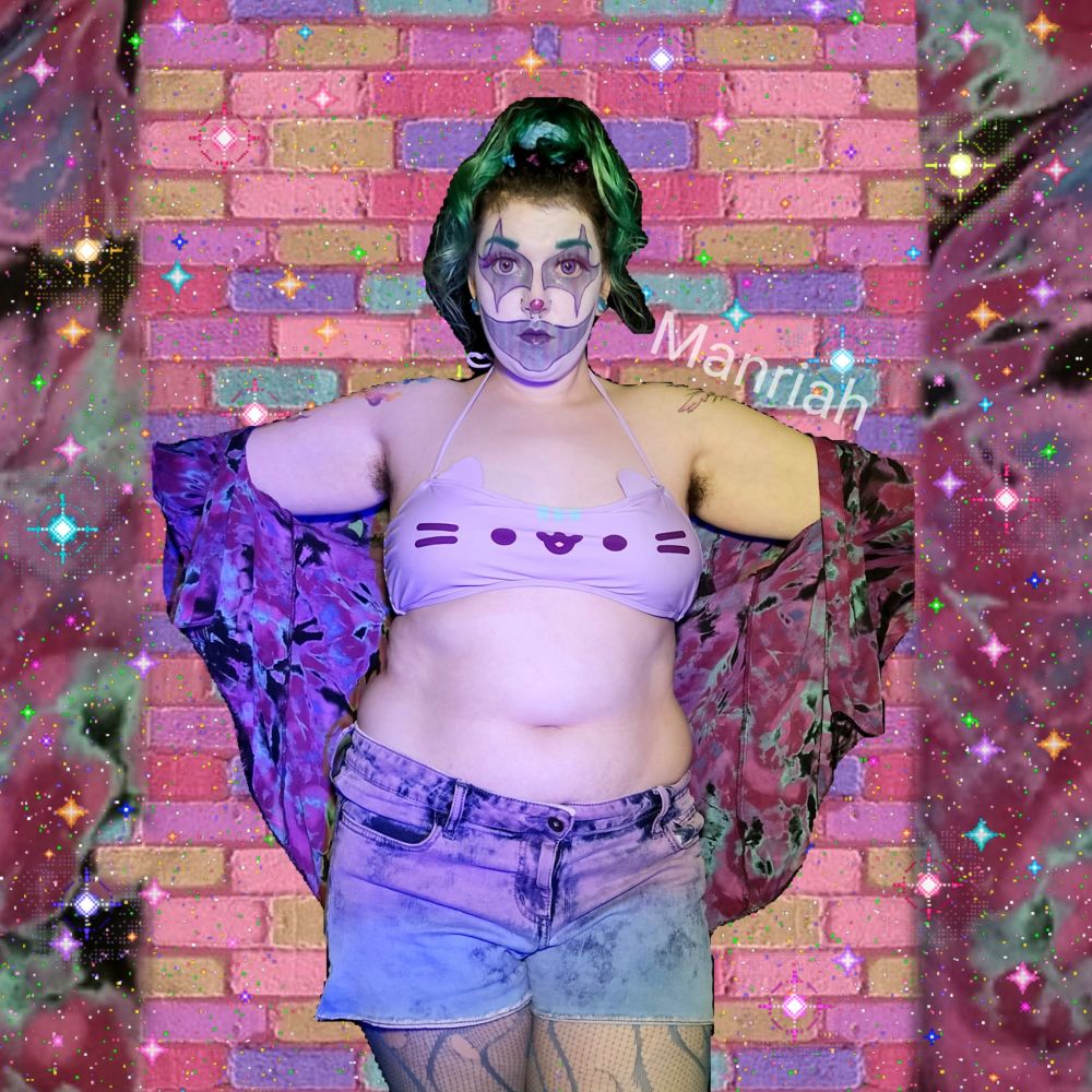Manriah wearing purple and blue striped clown makeup, a purple and blue tiedye shawl, a pusheen bikini top, purple and blue shorts, and blue fishnets