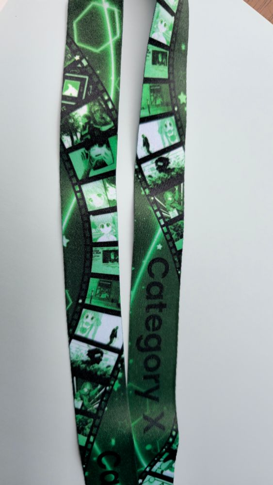 A green lanyard that says "category x" it has a film strip design with images from amvs within the strip.