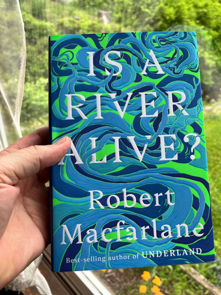 The book, "Is a River Alive?" held with a green background.