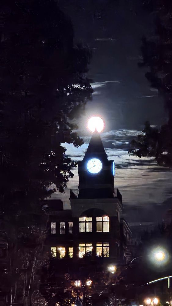 Full moon exactly placed at the tip of a clock tower, with some fuzz and distortion, Fairhaven WA USA.